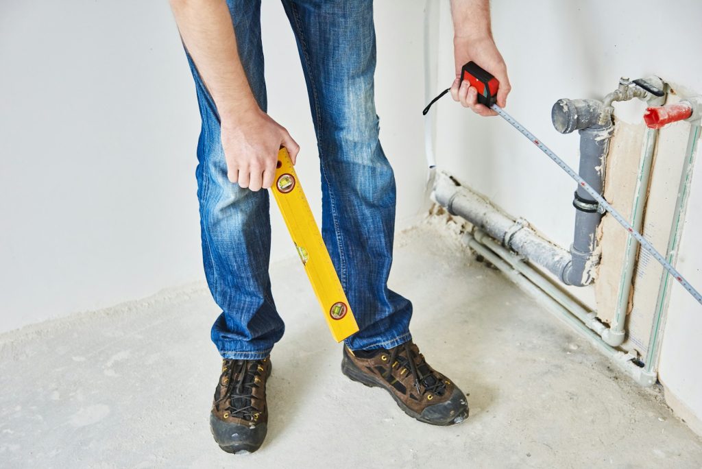 Plumber checks pipe vertical level after installation.